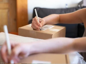persona poniendo a una etiqueta de envios información extra mientras lo escribe en el mismo paquete