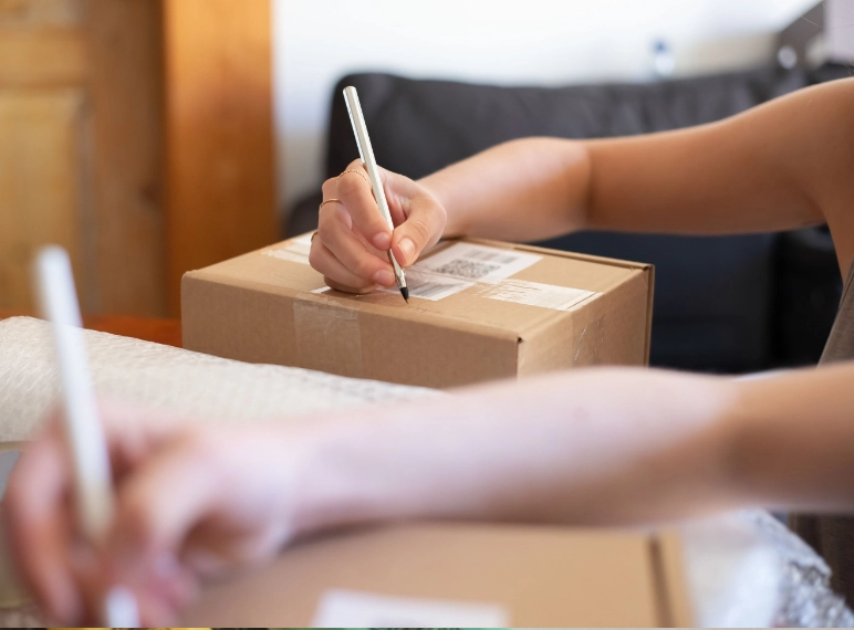 persona poniendo a una etiqueta de envios información extra mientras lo escribe en el mismo paquete
