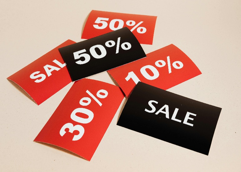 Etiquetas de descuentos en color rojo y negro con porcentajes del 10%, 30% y 50% y la palabra "SALE", esparcidas sobre un fondo neutro para campaña de Hot Sale.