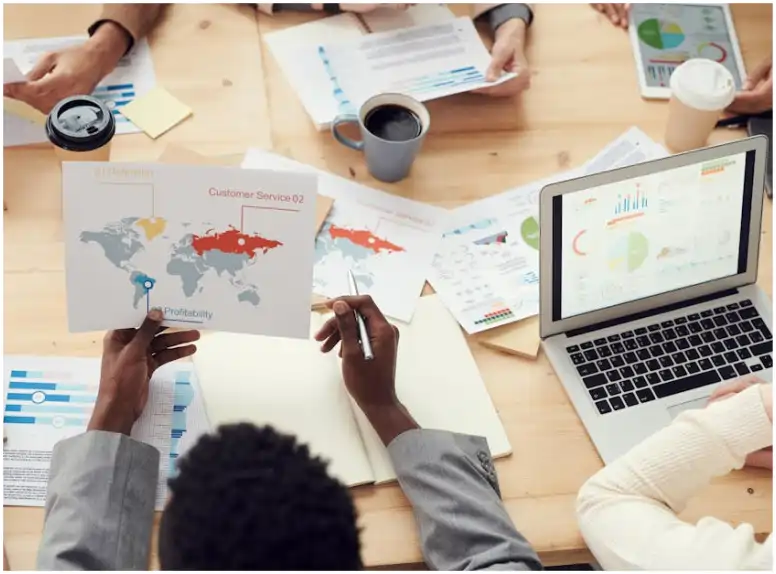 Equipo de trabajo analizando mapas y gráficas en una mesa para elegir la mejor paquetería para su estrategia de envío local.