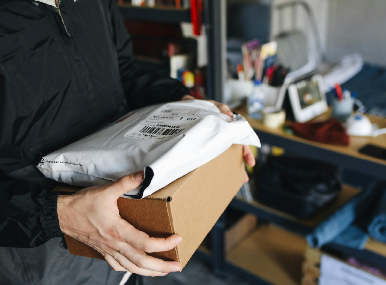 demostracion de paquetes que tiene una persona en mano que es una caja y una bolsa de plastico de envios