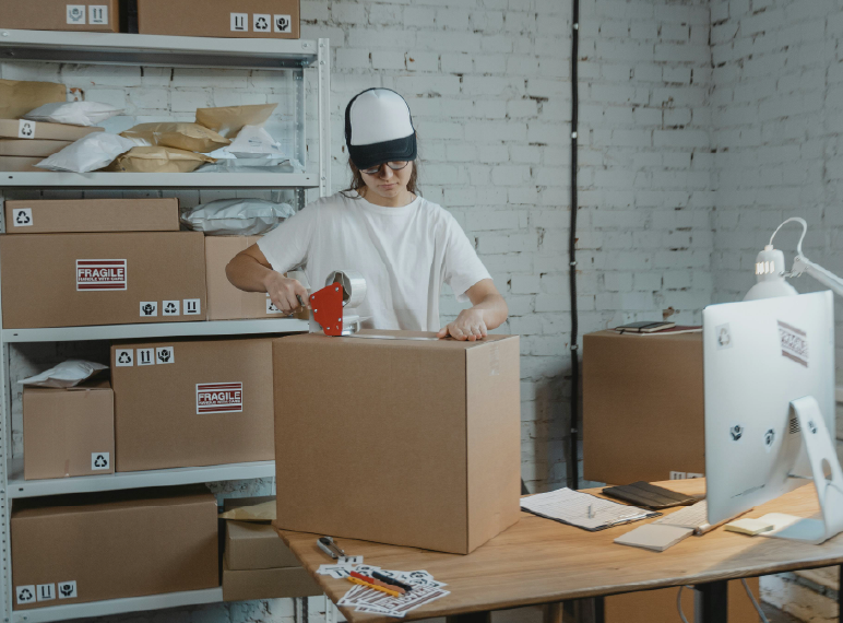 persona rodeada de paquetes que esta alistando para enviar a su destino