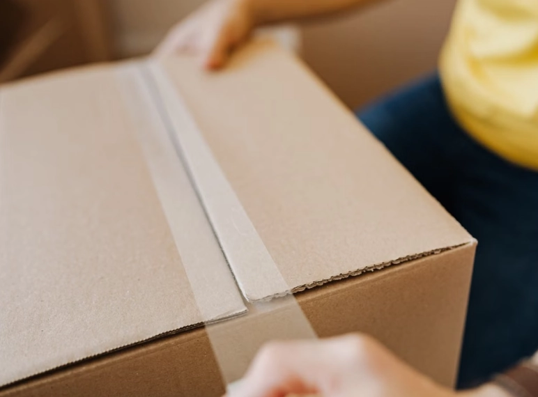 poniendo cinta a una caja para que este sellada y lista para enviarse